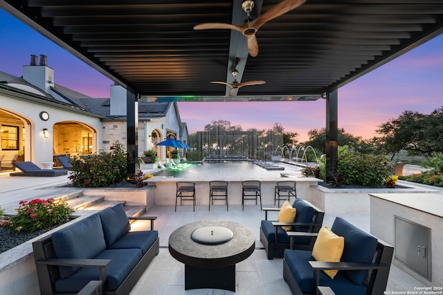 patio terrace at dusk with exterior kitchen, an outdoor living space with a fire pit, and exterior bar