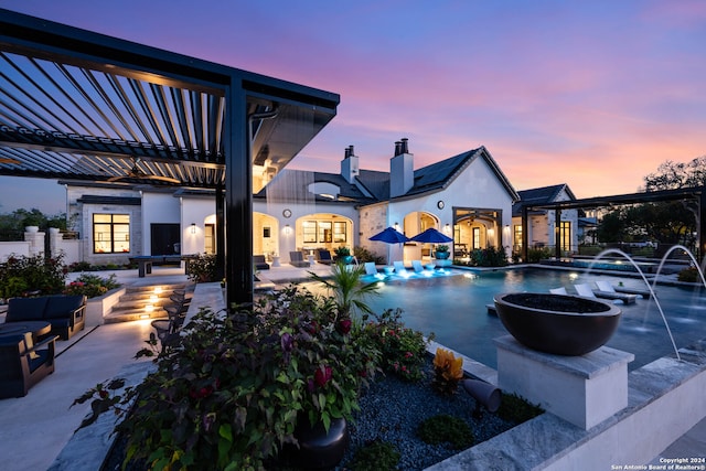 pool at dusk with pool water feature and a patio