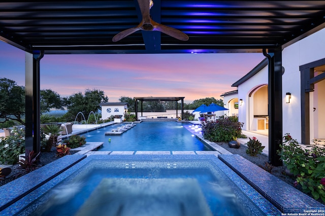 pool at dusk featuring pool water feature, a patio area, and an in ground hot tub