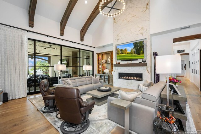 living room featuring a fireplace, beamed ceiling, high vaulted ceiling, and light hardwood / wood-style floors