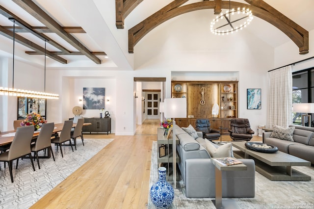 living room with a high ceiling, beam ceiling, light wood-type flooring, and a chandelier