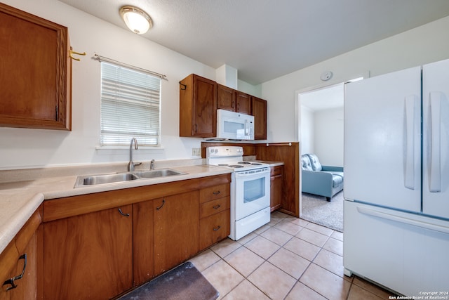 kitchen with light tile patterned floors, white appliances, sink, and a textured ceiling