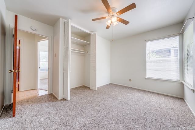 unfurnished bedroom with light carpet, multiple windows, ceiling fan, and a closet