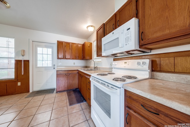 kitchen featuring white appliances, light tile patterned floors, and sink