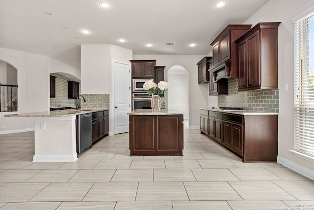 kitchen featuring a kitchen island, dark brown cabinetry, appliances with stainless steel finishes, and tasteful backsplash