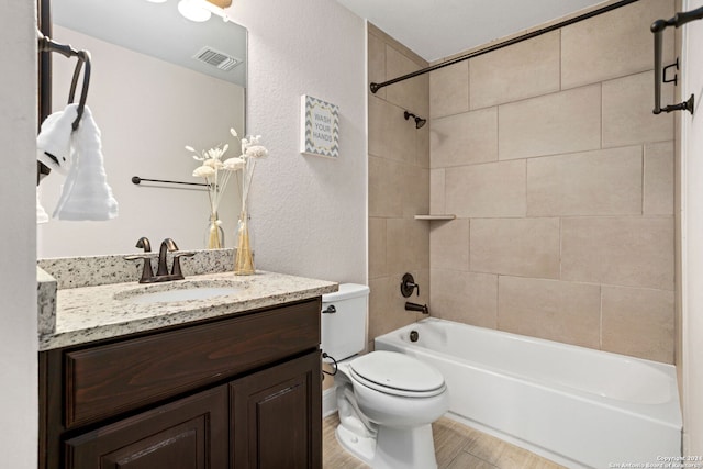 full bathroom with vanity, tiled shower / bath combo, and toilet