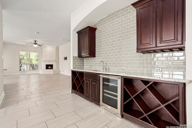 kitchen with a fireplace, light stone countertops, sink, and beverage cooler