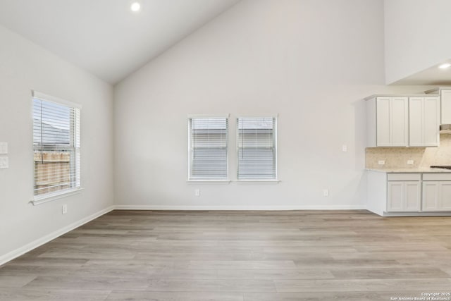 unfurnished living room with light wood-type flooring and high vaulted ceiling