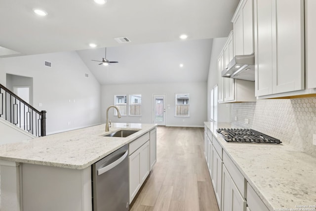 kitchen with light stone countertops, vaulted ceiling, stainless steel appliances, an island with sink, and sink