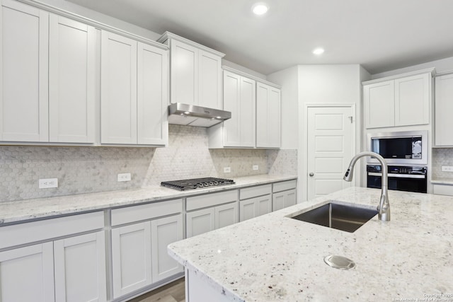 kitchen with sink, white cabinets, light stone counters, and appliances with stainless steel finishes