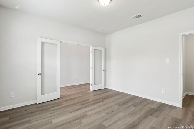 unfurnished bedroom with french doors and light hardwood / wood-style flooring