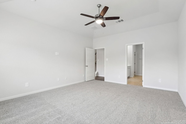 unfurnished bedroom featuring ceiling fan, light colored carpet, and ensuite bath