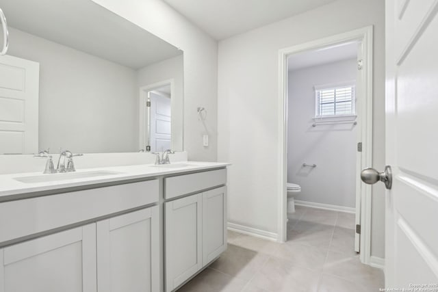 bathroom with toilet, vanity, and tile patterned floors