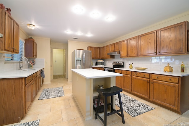 kitchen featuring a center island, stainless steel appliances, sink, light tile patterned flooring, and a breakfast bar area