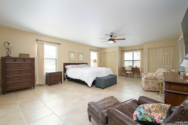 tiled bedroom featuring ceiling fan, multiple closets, and multiple windows