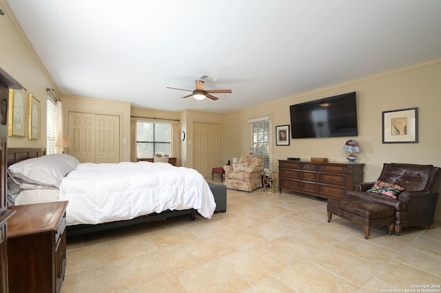 bedroom with crown molding, two closets, and ceiling fan