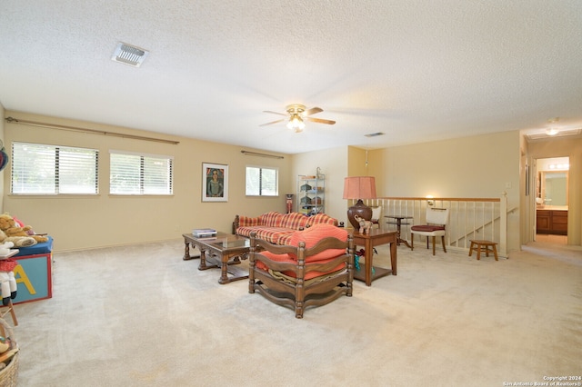 living room featuring ceiling fan, a wealth of natural light, light carpet, and a textured ceiling