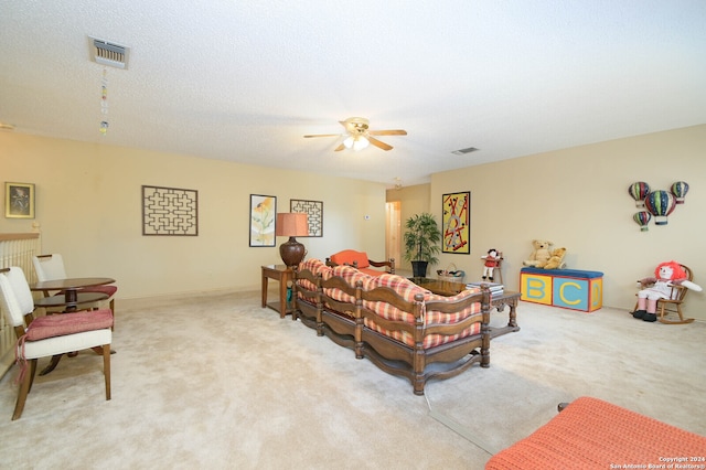 living room featuring light colored carpet, ceiling fan, and a textured ceiling