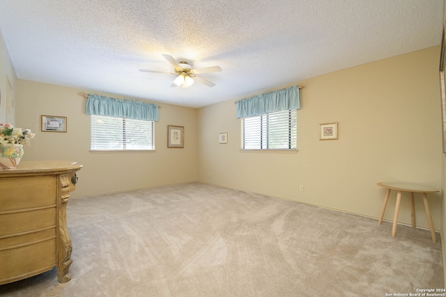 interior space with multiple windows, ceiling fan, and light colored carpet