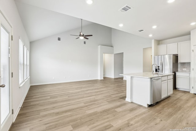 kitchen with dishwasher, light hardwood / wood-style flooring, an island with sink, tasteful backsplash, and white cabinetry