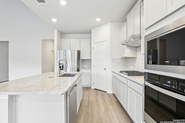 kitchen featuring a kitchen island with sink, backsplash, white cabinetry, appliances with stainless steel finishes, and sink