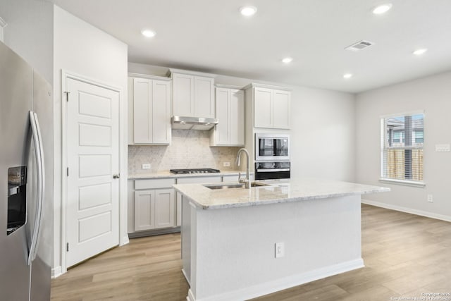 kitchen featuring stainless steel appliances, a kitchen island with sink, and white cabinetry