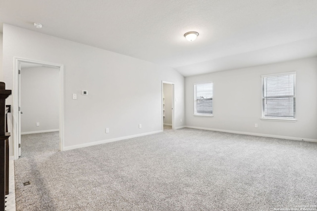 carpeted spare room with lofted ceiling