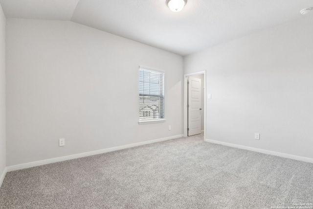 carpeted spare room featuring vaulted ceiling