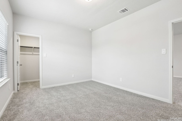 unfurnished bedroom with light colored carpet, a spacious closet, and a closet