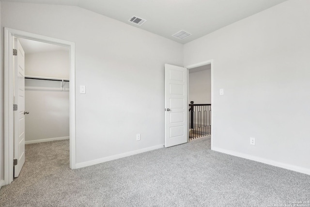 unfurnished bedroom featuring lofted ceiling, light colored carpet, a closet, and a spacious closet