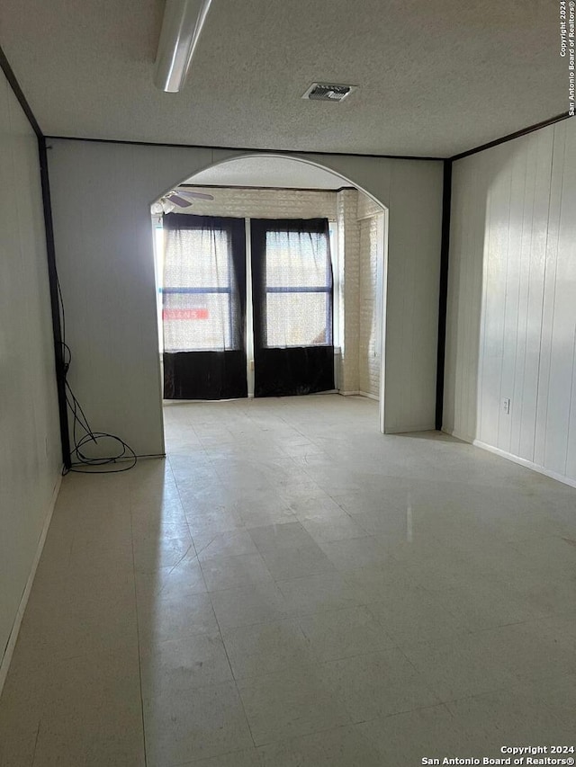 empty room featuring a textured ceiling and wooden walls