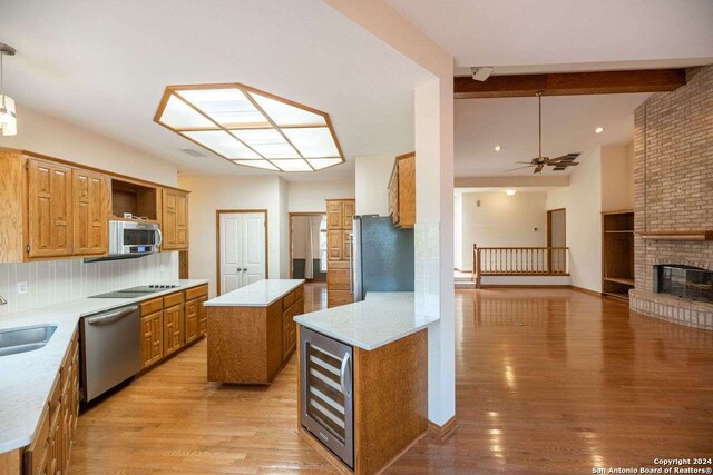 kitchen featuring beamed ceiling, decorative light fixtures, appliances with stainless steel finishes, a center island, and ceiling fan