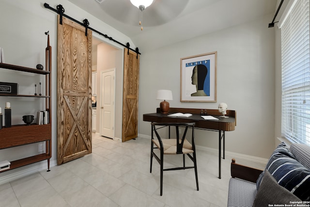 office with a barn door, light tile patterned flooring, vaulted ceiling, and ceiling fan