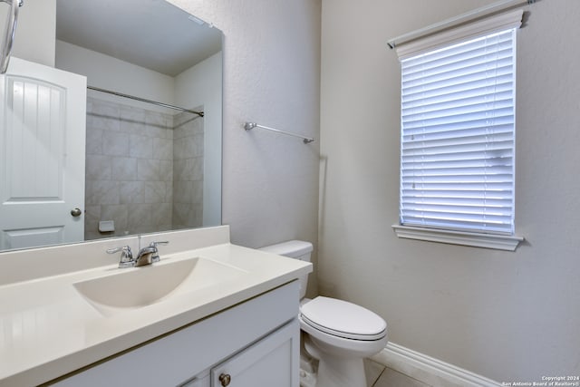 bathroom featuring tiled shower, vanity, toilet, and a wealth of natural light