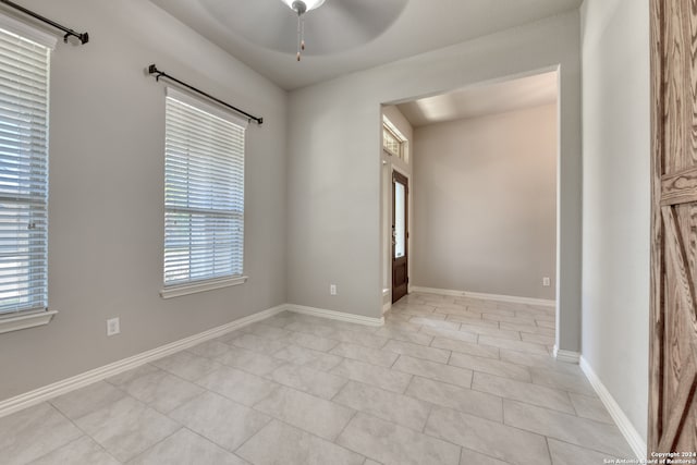 tiled empty room featuring ceiling fan and plenty of natural light