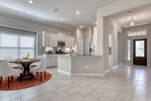 kitchen featuring appliances with stainless steel finishes, a wealth of natural light, kitchen peninsula, and white cabinets