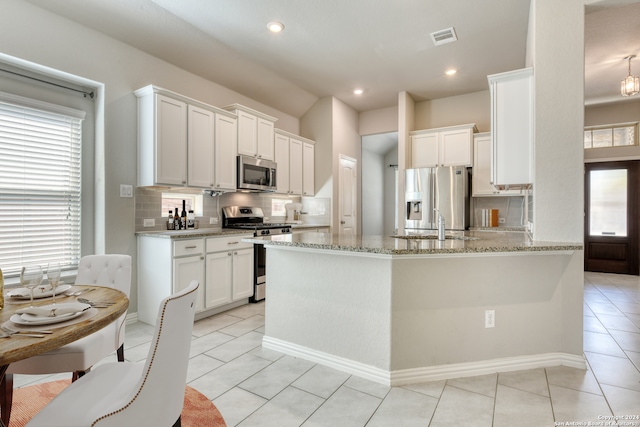 kitchen featuring appliances with stainless steel finishes, tasteful backsplash, white cabinets, light stone countertops, and light tile patterned floors