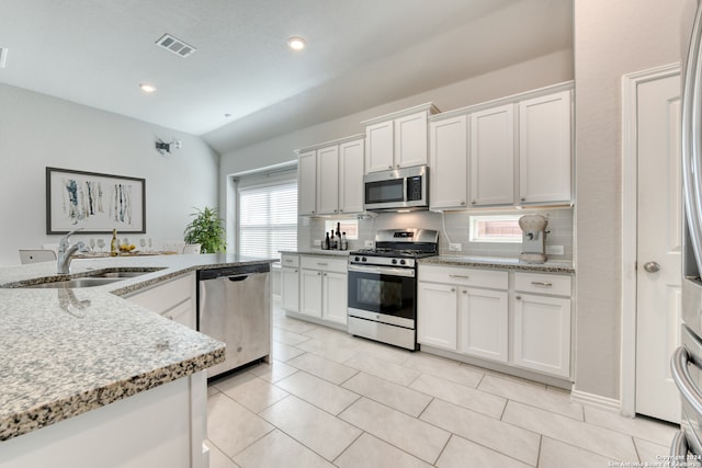 kitchen with light stone countertops, stainless steel appliances, sink, and white cabinetry