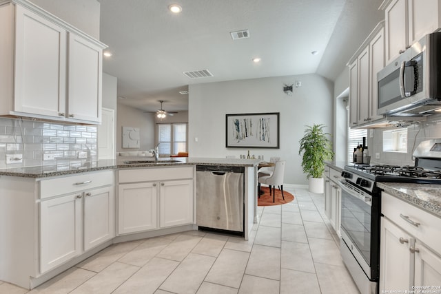 kitchen featuring decorative backsplash, light stone counters, white cabinets, stainless steel appliances, and ceiling fan