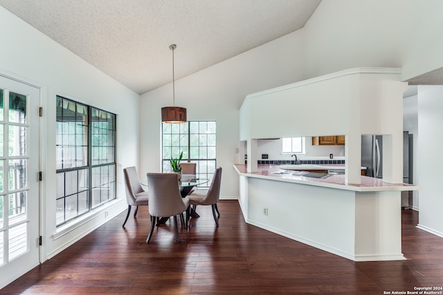 kitchen with hanging light fixtures, kitchen peninsula, dark hardwood / wood-style floors, and sink