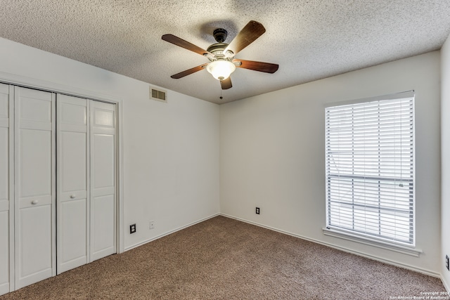 unfurnished bedroom featuring a textured ceiling, carpet, ceiling fan, and a closet