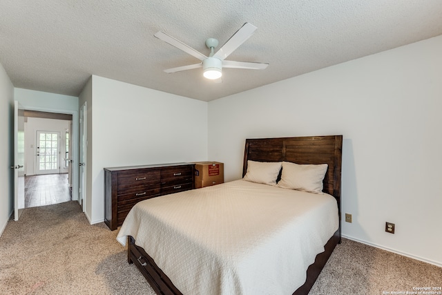 carpeted bedroom with ceiling fan and a textured ceiling