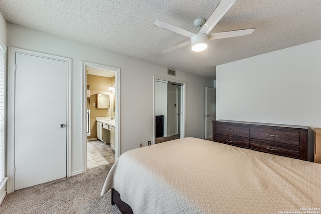 carpeted bedroom with a textured ceiling, ceiling fan, and connected bathroom