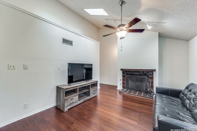 living room featuring vaulted ceiling with skylight, dark hardwood / wood-style floors, rail lighting, ceiling fan, and a textured ceiling