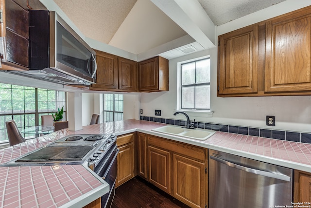 kitchen featuring a healthy amount of sunlight, tile countertops, stainless steel appliances, and sink