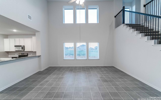 413 Tims Way, Seguin, TX 78155 - unfurnished living room with a towering ceiling, ceiling fan, stairway, and baseboards