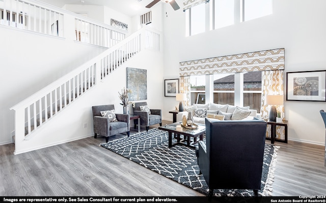 living room with hardwood / wood-style floors, ceiling fan, and a towering ceiling