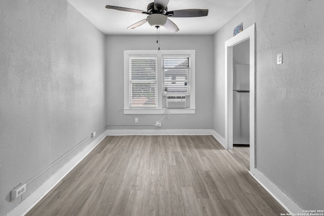 spare room featuring cooling unit, ceiling fan, and light hardwood / wood-style floors