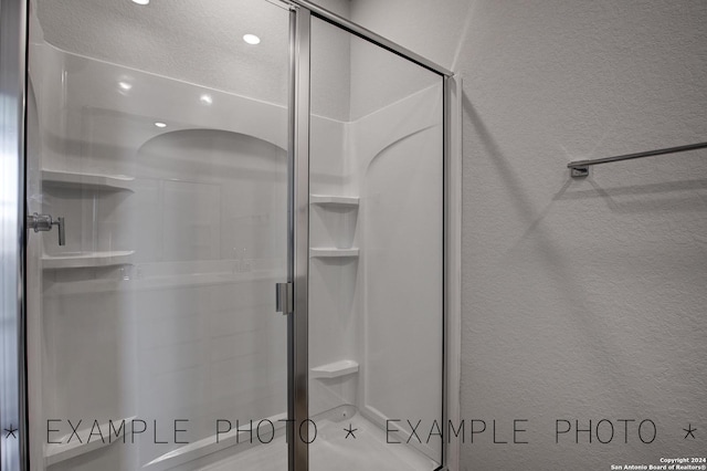 bathroom with a textured ceiling and an enclosed shower