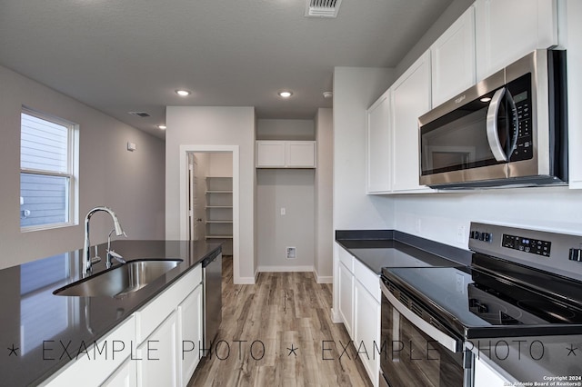 kitchen with stainless steel appliances, light wood-type flooring, sink, and white cabinetry